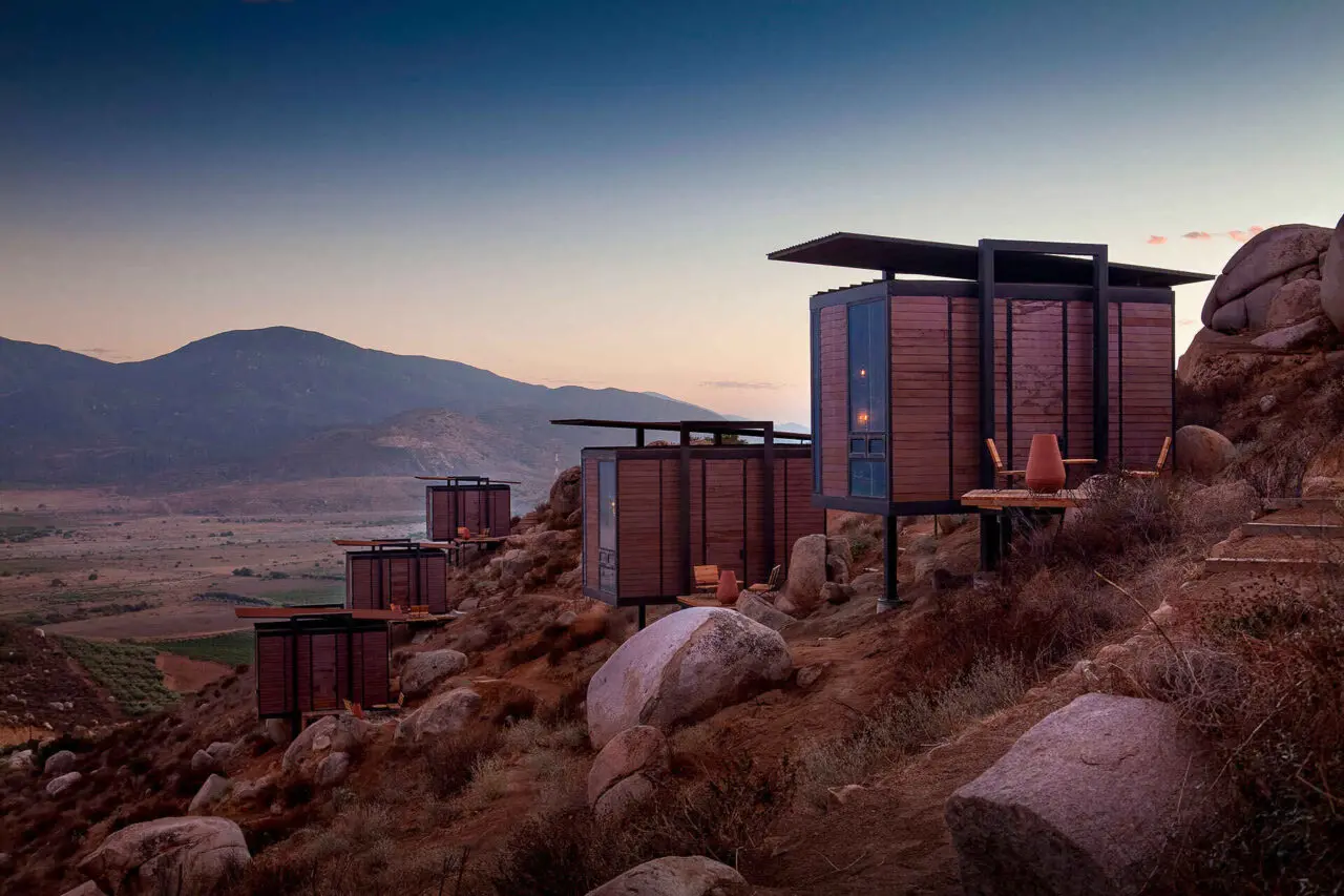 A modern winery in Valle de Guadalupe with a view of the vineyards and desert landscape.
