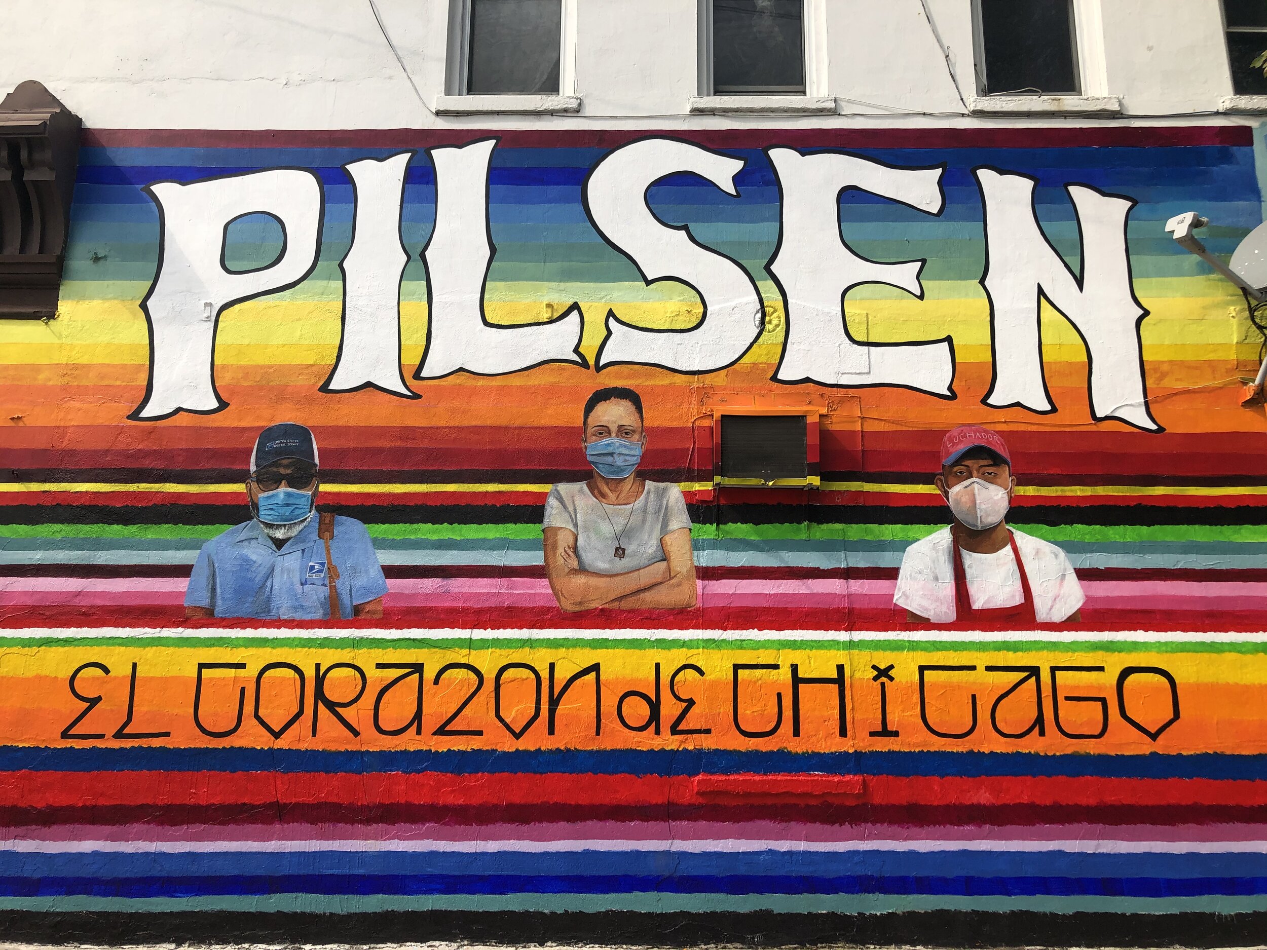 A vibrant and colorful street mural on a brick building in the Pilsen neighborhood of Chicago.