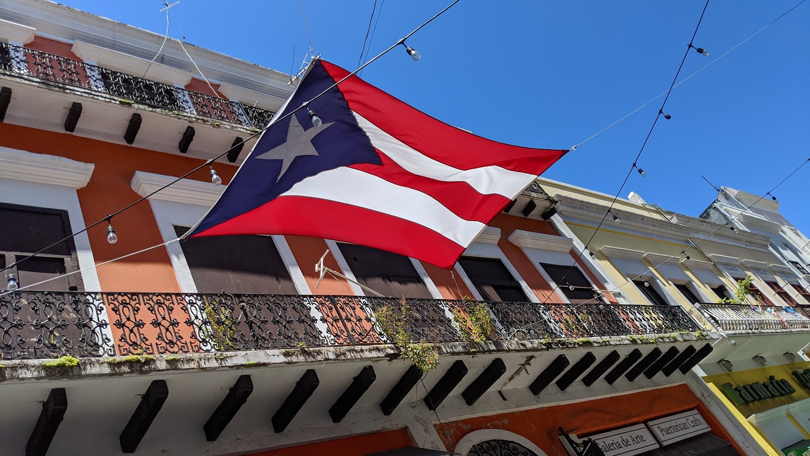 Puerto Rican flag strung above colorful balconied buildings in Old San Juan