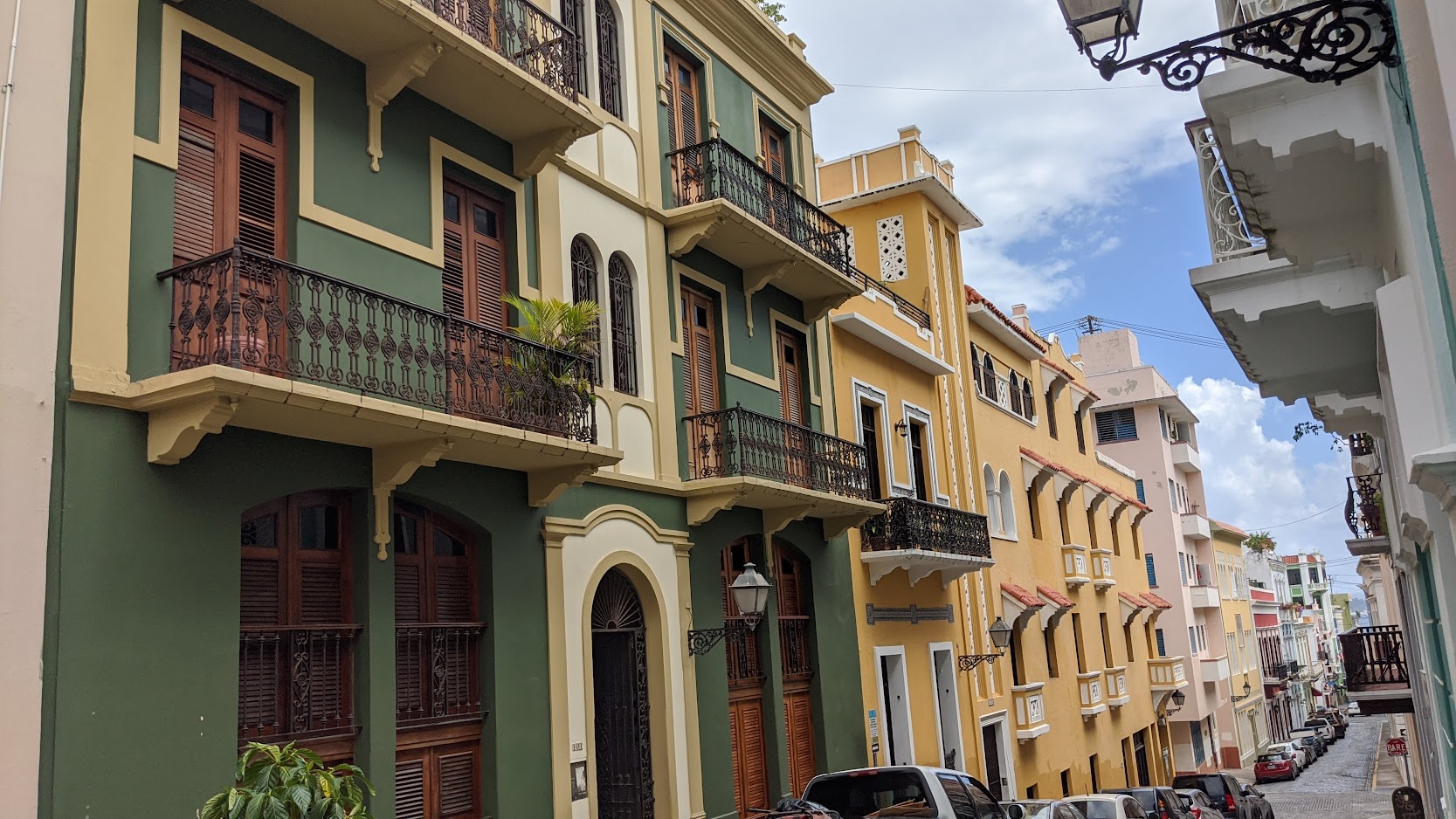 Green and yellow colonial facades with wrought-iron balconies in Old San Juan