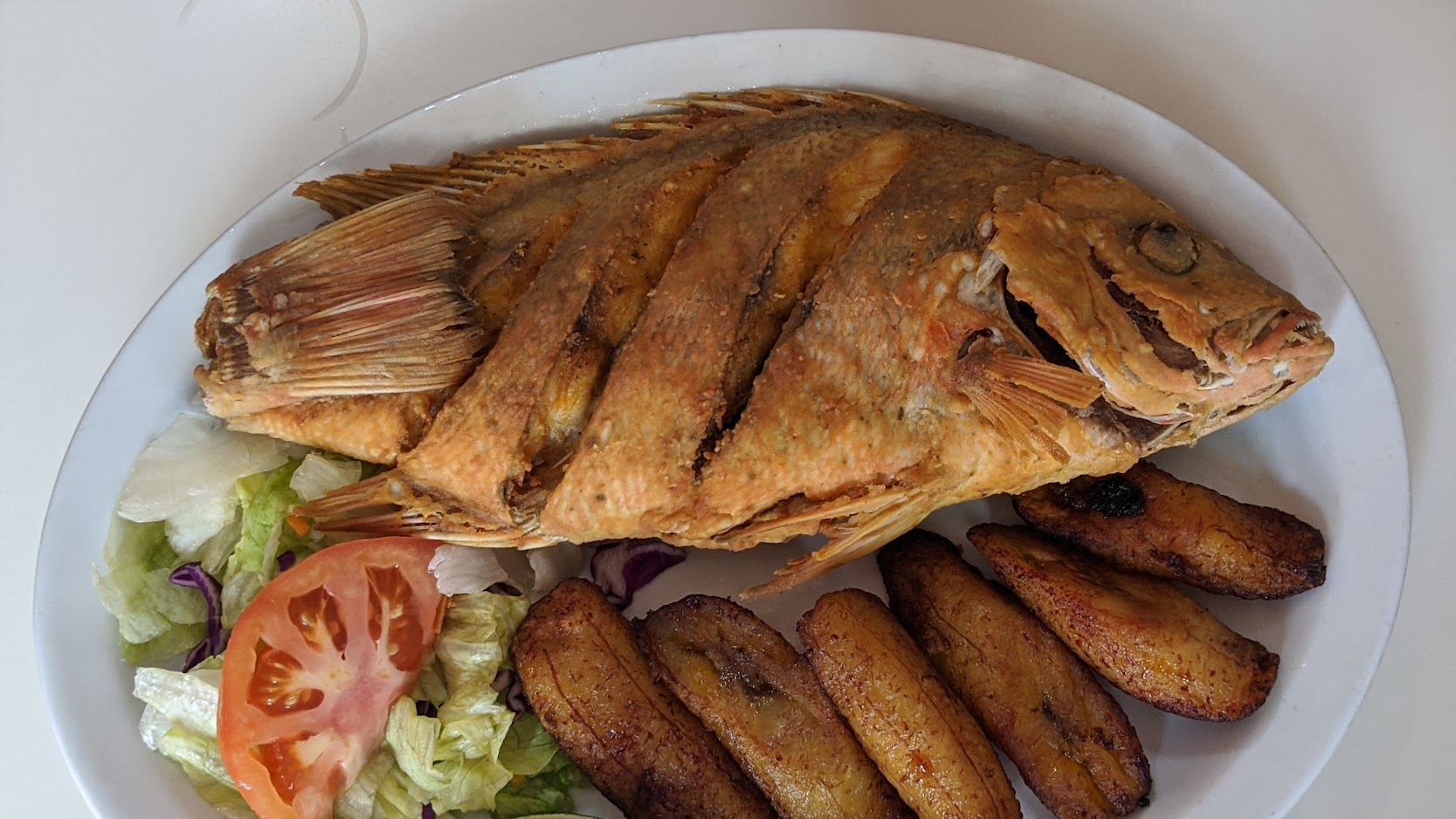 Whole fried fish served with side salad and sweet fried plantains